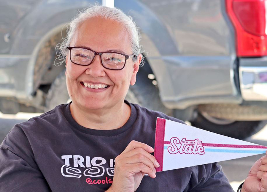 A TRiO employee holds up a small Aggie flag. 