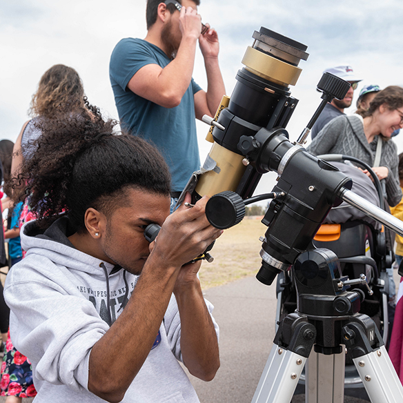 a student looks through a telescope