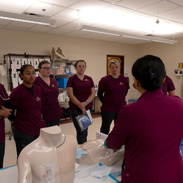 Nursing students listen to a professor in a classroom.