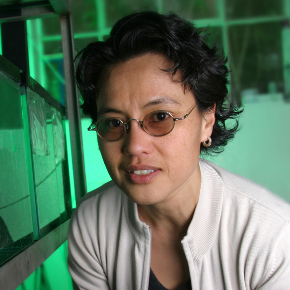 biology professor Graciela Unguez poses next to a bank of fish aquariums in her laboratory.