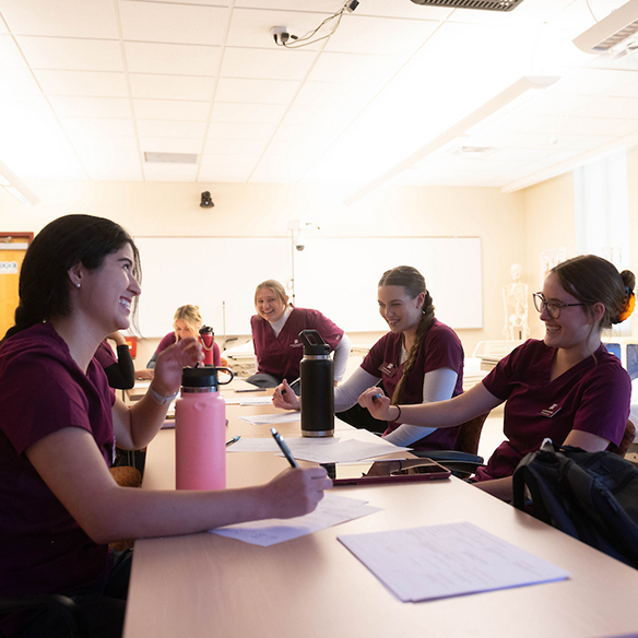 A group of public health students laughing with each other in the classroom