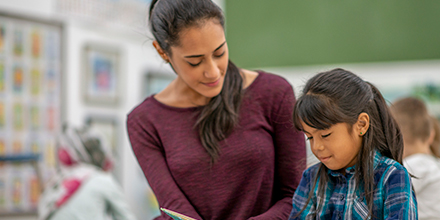 Elementary school teacher working with hispanic girl