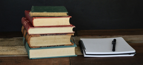 a stack of books and a notebook in front of a chalkboard